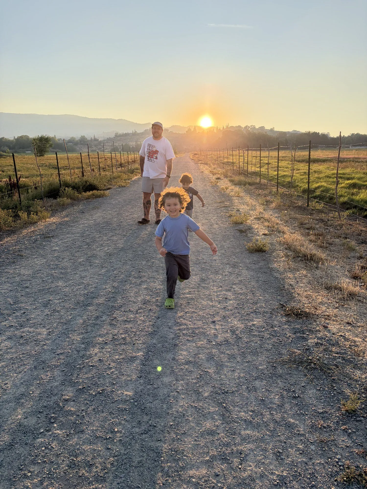 Family running on a dirt road at sunset
